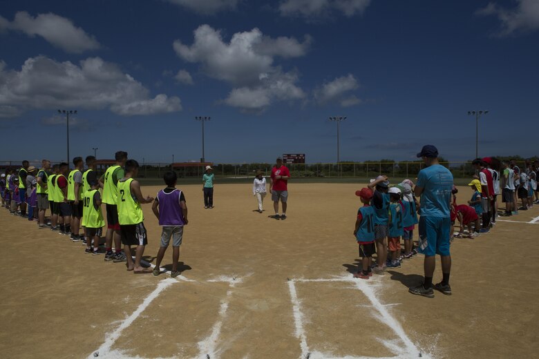 Gunnery Sgt. David Devine shares a few words of encouragement and laughs before kicking off a friendly game of kickball July 15 aboard Camp Kinser, Okinawa, Japan. Kinser’s Single Marine Program and the Morinoko and Miyagi Children Centers came together for a day of fun. Devine is the Camp Kinser operations and camp guard chief.