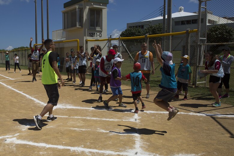 Players cheer with excitement during a friendly game of kickball July 15 aboard Camp Kinser, Okinawa, Japan. Kinser’s Single Marine Program and the Morinoko and Miyagi Children Centers came together for a day of fun. During the game, on defense, Marines took positions and shared them with a few of the children, helping them play and learn.