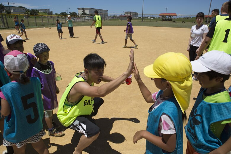 Cpl. Kevin Nguyen congratulates a child after a friendly game of kickball July 15 aboard Camp Kinser, Okinawa, Japan. Kinser’s Single Marine Program and the Morinoko and Miyagi Children Centers came together for a day of fun. Nguyen is a Camp Kinser SMP representative.