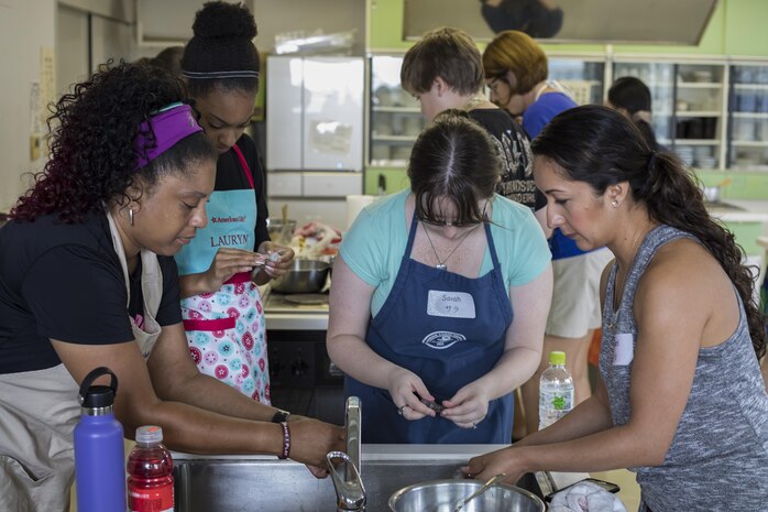 Marine Corps Air Station Iwakuni residents work together to devein shrimp for sushi and tempura during a Japanese cooking class at Santopia in Otake, Japan, July 25, 2017. Air station residents traveled with the Cultural Adaptation Program to partake in the class where they learned to properly prepare and cook sushi, tempura and a Japanese pudding dessert. The class gave a common purpose for participants to work together and learn Japanese cooking skills that can be utilized within their own homes. (U.S. Marine Corps photo by Cpl. Joseph Abrego)
