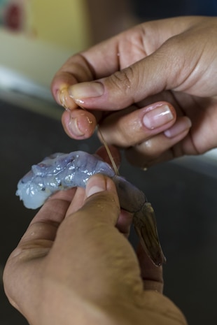 A Marine Corps Air Station Iwakuni resident deveins shrimp for sushi and tempura during a Japanese cooking class at Santopia in Otake, Japan, July 25, 2017. Air station residents traveled with the Cultural Adaptation Program to partake in the class where they learned to properly prepare and cook sushi, tempura and a Japanese pudding dessert. The class gave a common purpose for participants to work together and learn Japanese cooking skills that can be utilized within their own homes.  (U.S. Marine Corps photo by Cpl. Joseph Abrego)