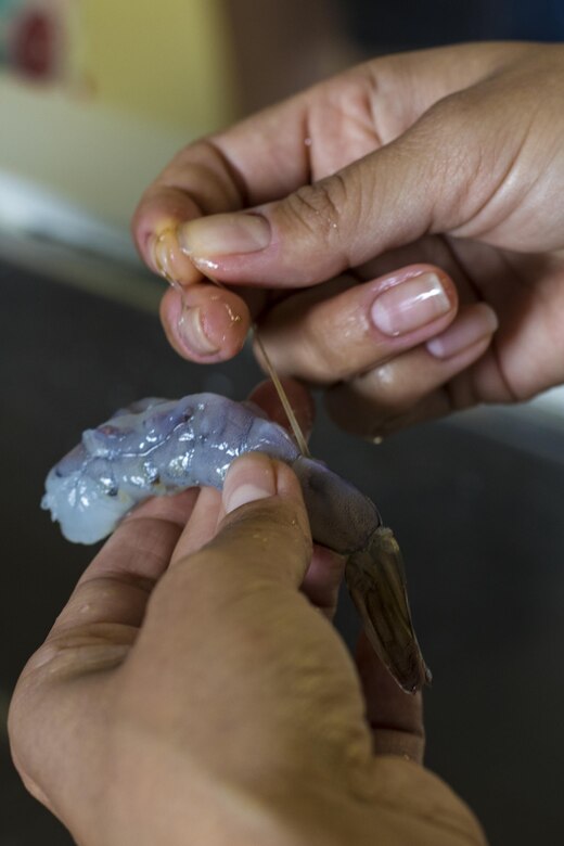 A Marine Corps Air Station Iwakuni resident deveins shrimp for sushi and tempura during a Japanese cooking class at Santopia in Otake, Japan, July 25, 2017. Air station residents traveled with the Cultural Adaptation Program to partake in the class where they learned to properly prepare and cook sushi, tempura and a Japanese pudding dessert. The class gave a common purpose for participants to work together and learn Japanese cooking skills that can be utilized within their own homes.  (U.S. Marine Corps photo by Cpl. Joseph Abrego)