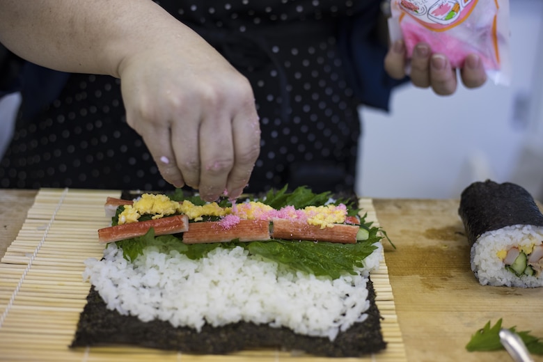 Sachiko Tamura, a chef with the Iwakuni City Food Promotion Association, tops her sushi with denbu, a fish flake seasoning, during a Japanese cooking class at Santopia in Otake, Japan, July 25, 2017. Marine Corps Air Station Iwakuni residents traveled with the Cultural Adaptation Program to partake in the class where they learned to properly prepare and cook sushi, tempura and a Japanese pudding dessert. The class gave a common purpose for participants to work together and learn Japanese cooking skills that can be utilized within their own homes. (U.S. Marine Corps photo by Cpl. Joseph Abrego)
