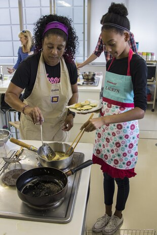 Elizabeth Scott, left, and Lauryn Scott, Marine Corps Air Station Iwakuni residents, cook tempura during a Japanese cooking class at Santopia in Otake, Japan, July 25, 2017. During the class, participants learned new techniques to aid in their cooking such as using mayonnaise to help tempura batter stick to vegetables. The class gave a common purpose for participants to work together and learn Japanese cooking skills that can be utilized within their own homes.  (U.S. Marine Corps photo by Cpl. Joseph Abrego)