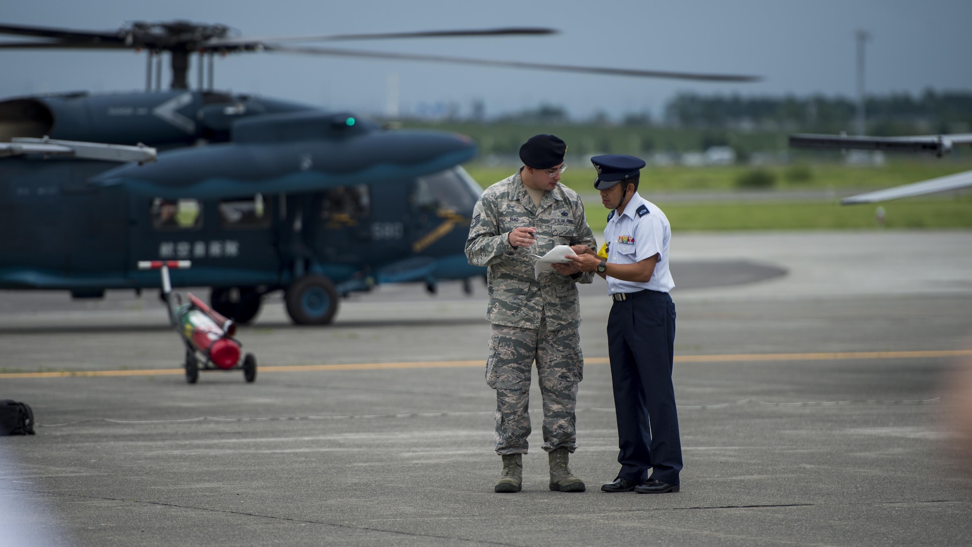 U.S. Air Force Staff Sgt. Garrett Pako, left, a 35th Security Forces Squadron base defense operations controller, speaks with a Japan Air Self-Defense security member, right, during the Chitose Air Show at Chitose Air Base, Japan, July 23, 2017. Security forces also sends an antiterrorism representative, who surveys the area, researches possible threats within the area and locates discrepancies that may hinder keeping resources safe. (U.S. Air Force Staff Sgt. Deana Heitzman)