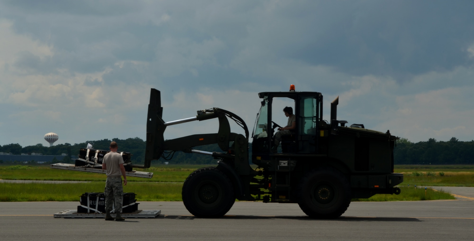 Senior Airman Ke Sherman, 103rd Logistics Readiness Squadron air transportation specialist, directs Senior Airman Shannon Carney, also an air transportation specialist assigned to the 103rd LRS, in lifting cargo pallets offloaded from the C-130 July 11, at the Dogpatch. Sherman, who frequently operates the forklift, was given the opportunity to train Carney in how to use the machine.
