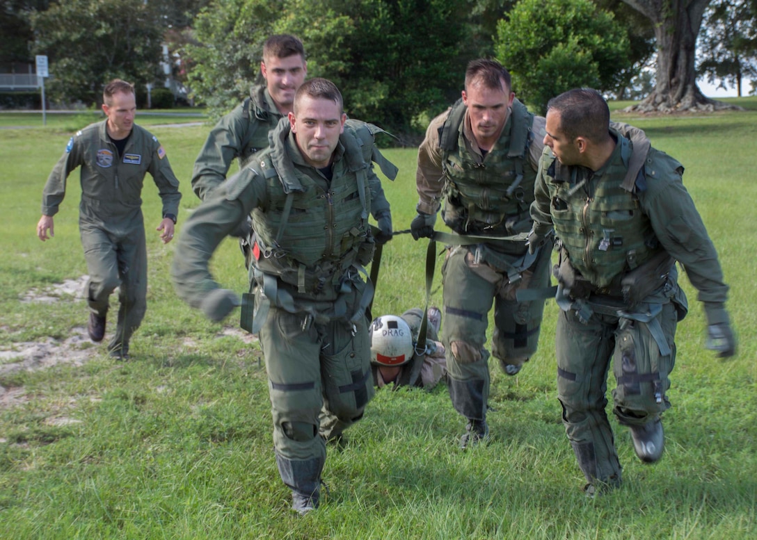 Students simulate turbulent landing conditions during a parachute survival training scenario as Navy Lt. Joshua Muffett, left, observes. Navy photo by Petty officer 2nd Class Michael J. Lieberknecht