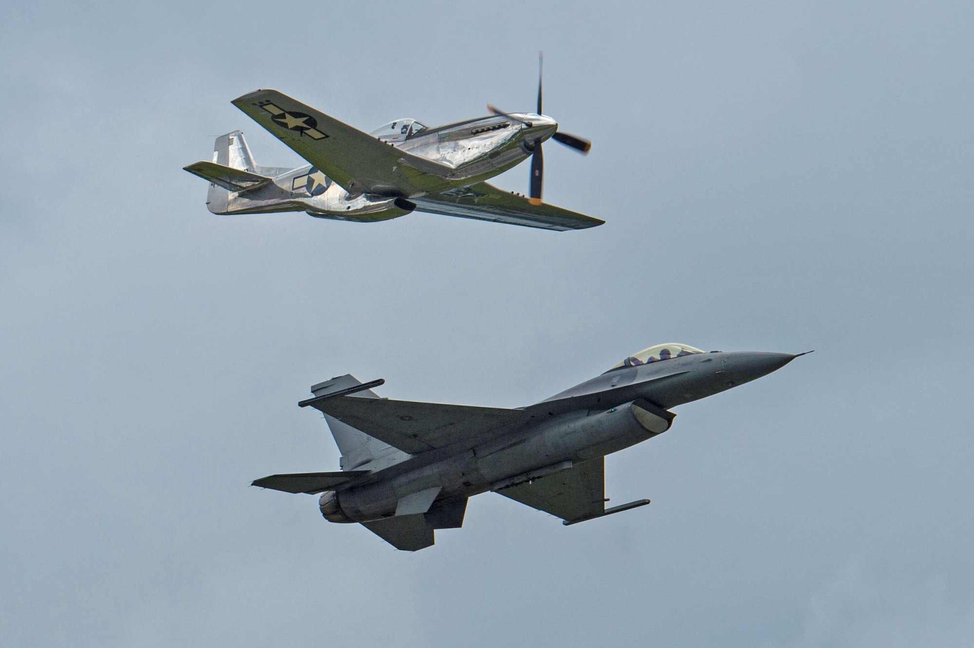 A P-51 Mustang flies above an F-16CM Fighting Falcon during a Heritage Flight performance at the New York Air Show at Stewart International Airport, N.Y., July 1, 2017. The 20th Fighter Wing, created July 28, 1947, began its journey flying P-51D Mustangs and currently flies F-16CM Fighting Falcons, providing combat-ready F-16 airpower and suppression of enemy air defenses. (U.S. Air Force photo by Airman 1st Class Sean Sweeney)