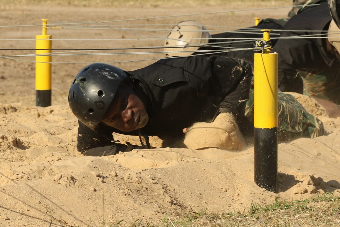 A Guyanese comando crawls beneath wires during a Fuerzas Comando obstacle course July 24, 2017, in Vista Alegre, Paraguay. This competition increases training knowledge and furthers interoperability between countries in the Western Hemisphere.  (U.S. Army photo by Sgt. Joanna Bradshaw/Released)