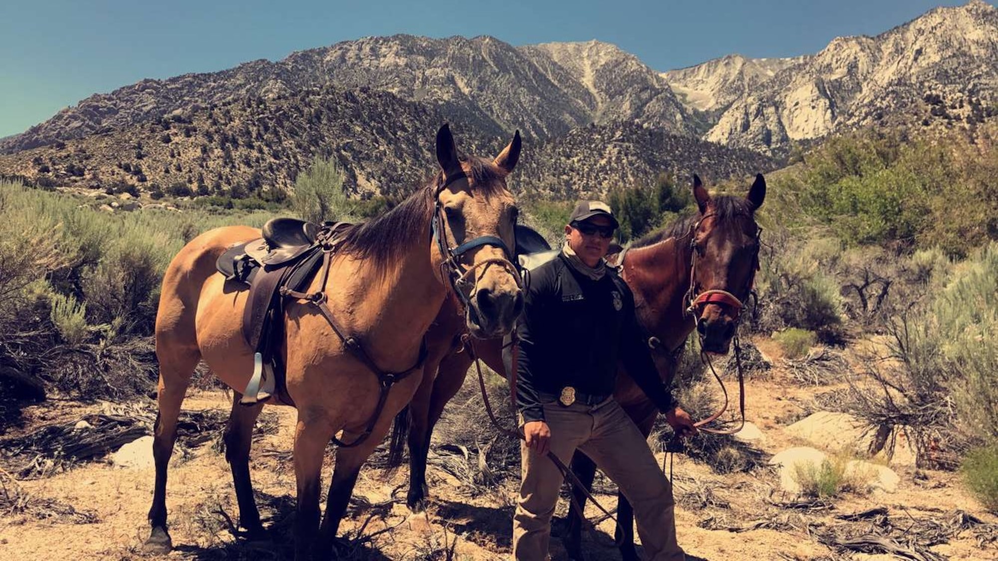 Staff Sgt. Elias Romero, 30th Security Forces Squadron Mounted Horse Patrol NCOIC, takes a photo with Duke, Military Working Horse, and Trooper, Military Working Horse, June 29, 2017, Lone Pine, Calif. The Vandenberg Mounted Horse Patrol was requested nearly a week after a RQ-4 Global Hawk unmanned surveillance aircraft assigned to the 9th Reconnaissance Wing at Beale Air Force Base crashed during a trip back to its home station, June 21. (courtesy photo)