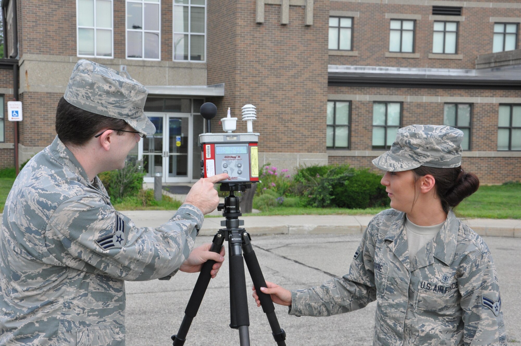 Senior Airman Alex Shuttleworth, Bioenvironmental Engineering journeyman, and Airman 1st Class Taylor Osborne, Bioenvironmental Engineering apprentice, read data from the wet bulb globe temperature measuring instrument July 14 near Bldg. 675, Area B, Wright-Patterson Air Force Base. (U.S. Air Force photo/W. Eugene Barnett)