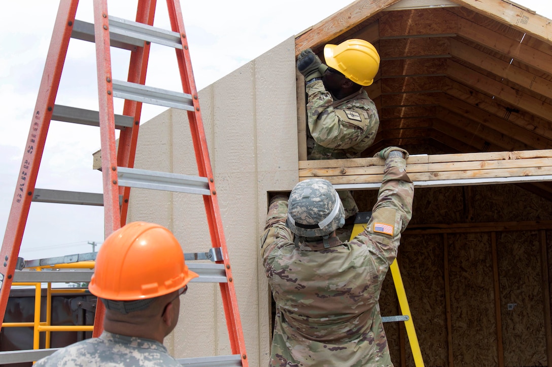 New York Army National Guardsmen attach a piece of siding to a shed being constructed during their unit's annual training at Fort Drum, N.Y., July 19, 2017. Army National Guard photo by Spc. Amouris Coss