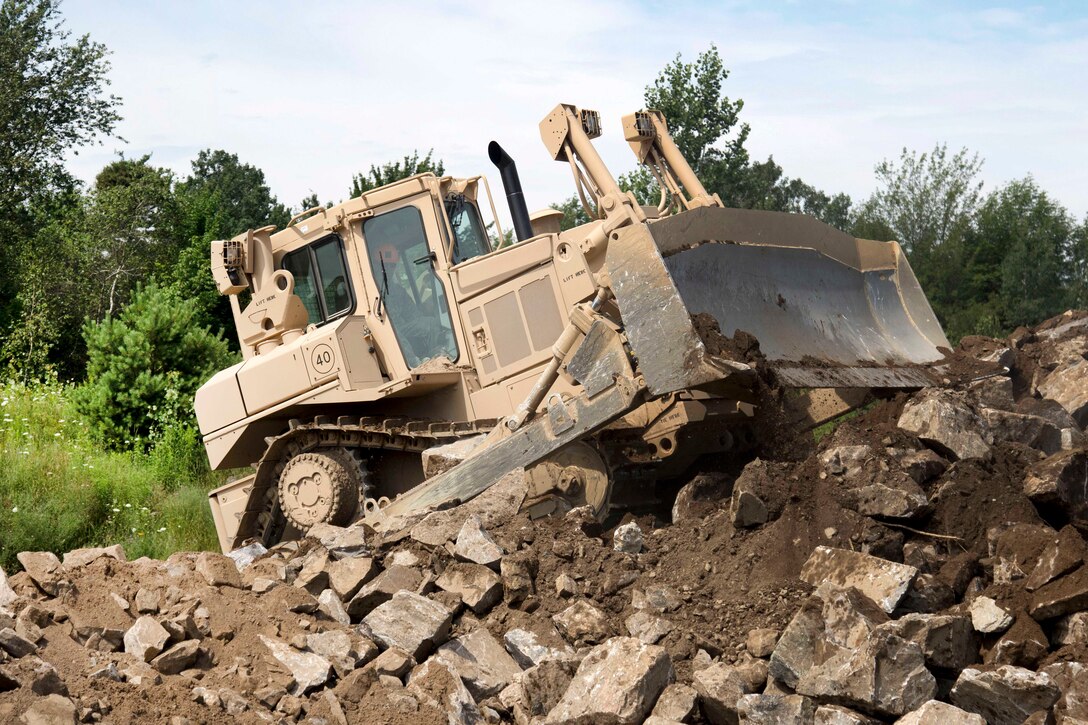 A New York Army National Guardsman operates a bulldozer to pile up boulders and dirt during annual training at Fort Drum, N.Y., July 20th, 2017. Army National Guard photo by Spc. Amouris Coss