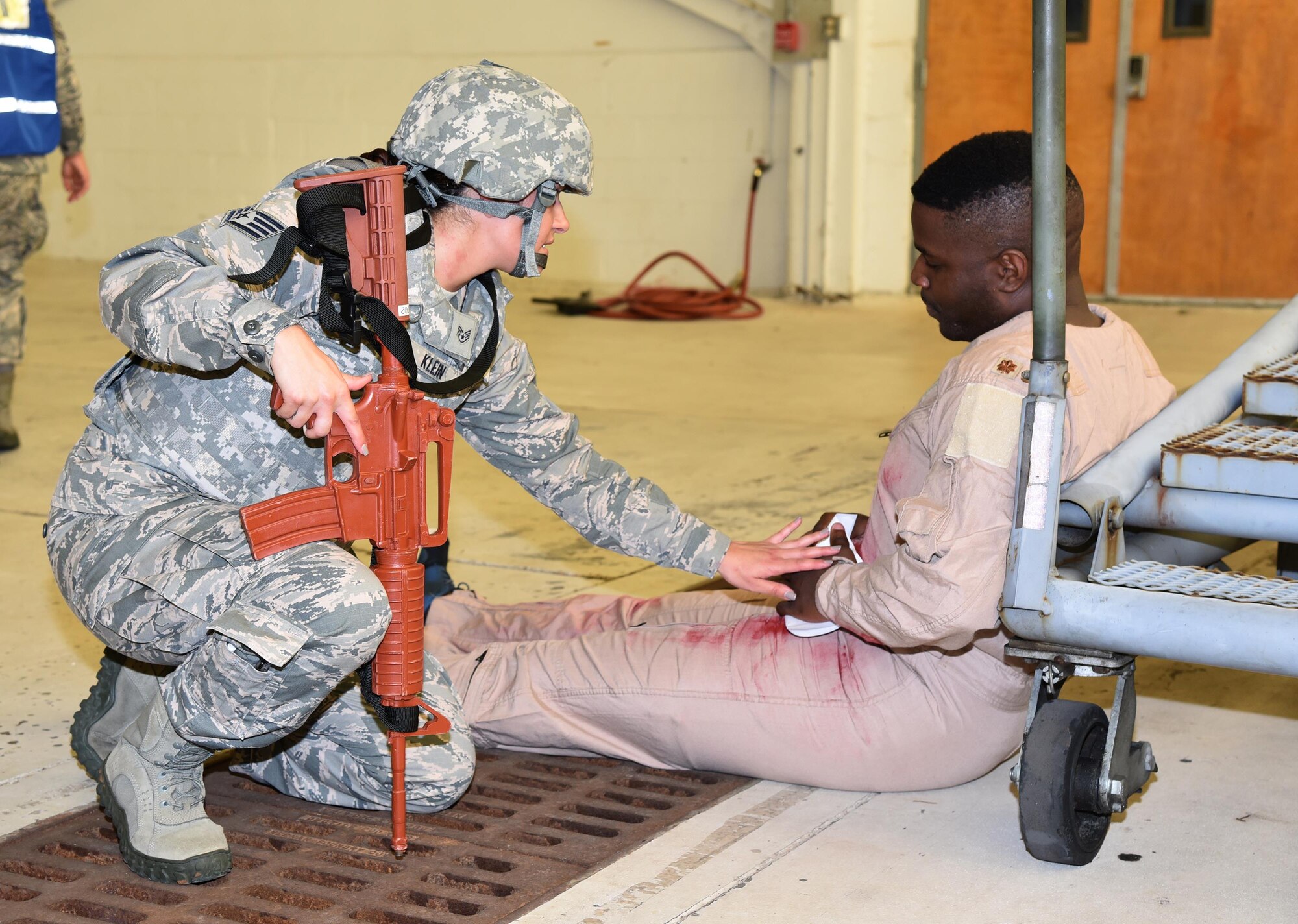 Staff Sgt. Hali Klein, 45th Security Forces Squadron, comforts active shooter exercise victim Airman 1st Class Ramon Thomas, 45th Comptroller Squadron, as they wait for medical teams to arrive July 25, 2017 in Hangar 750. Pararescuemen with the 308th Rescue Squadron and firefighters with the 45th Civil Engineer Squadron worked together at the crime scene to tend to the victims and load them into ambulances for transport to the hospital. The joint exercise between the 920th Rescue Wing and 45th Space Wing tested the units’ ability to work together in an emergency situation. (U.S. Air Force photo/Tech. Sgt. Lindsey Maurice)