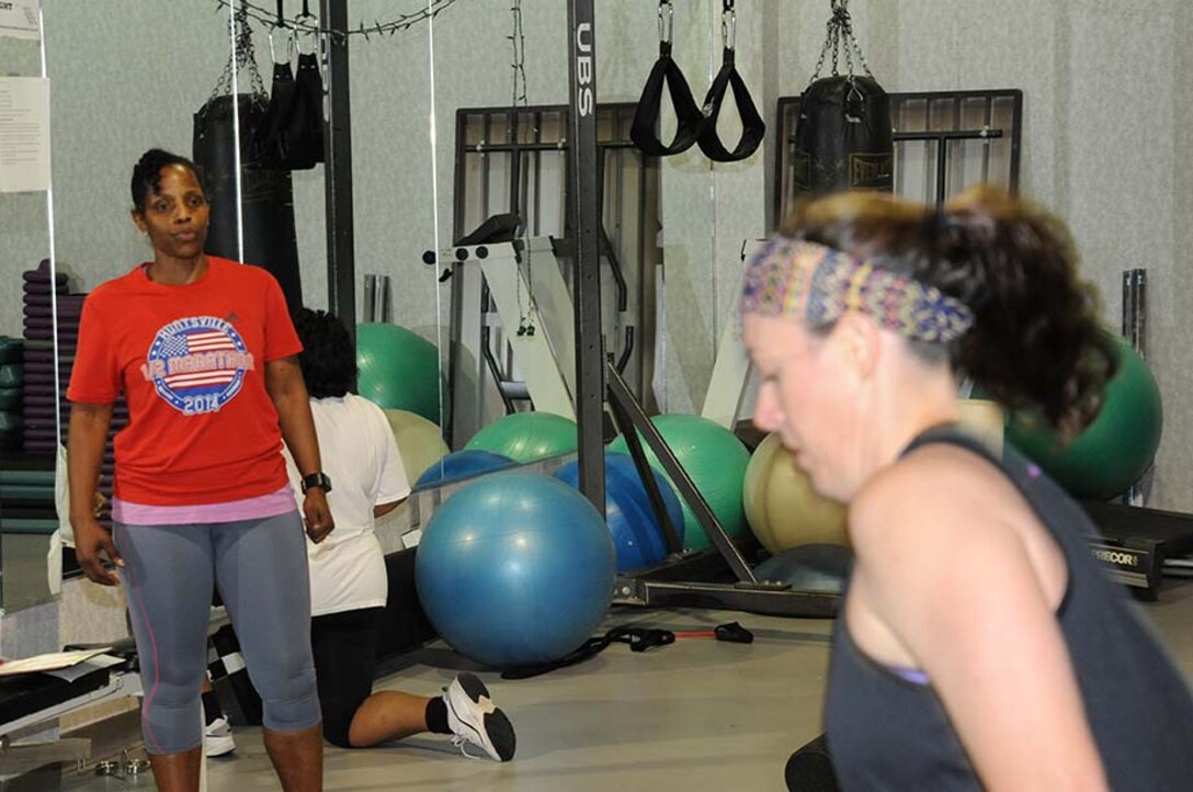 Dee Benson, left, provides motivation and encouragement to Amanda Sticker during a recent lunch hour strength and conditioning class at the U.S. Army Engineering and Support Center, Huntsville. Benson says wellness helps employees perform better with customers and teammates.