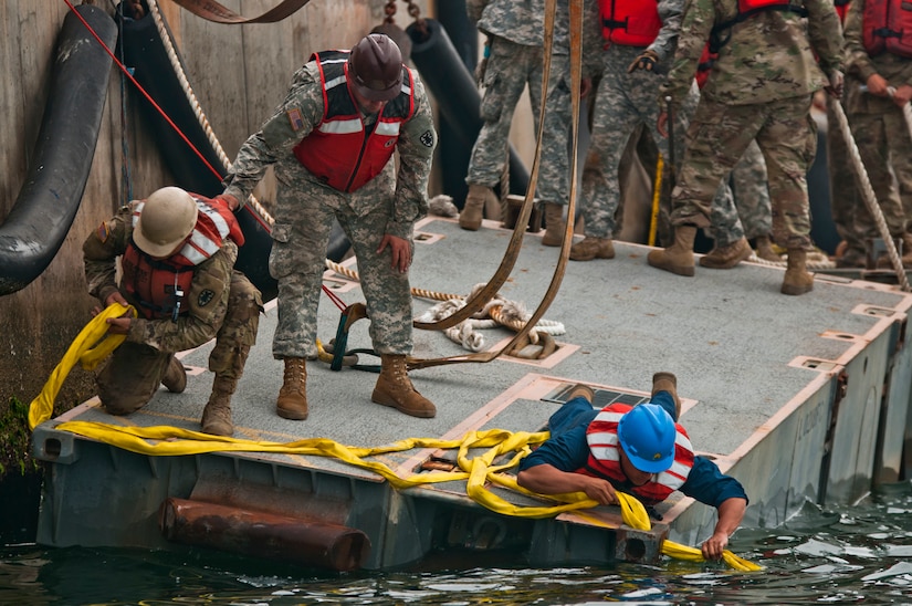 U.S. Army watercraft operators and engineers assemble a roll-on/roll-off discharge facility during training at the Port of San Diego on July 16, 2017. The RRDF is a causeway is used to quickly move supplies from ships to shore. U.S. Army Reserve Command Soldiers are participating in Exercise Big LOTS West, a joint military training exercise designed to reinforce the 1394th Transportation Brigade's ability to rapidly deploy vital combat equipment to an operational environment. (Photo by U.S. Army Reserve Sgt. David L. Nye, 301st Public Affairs Detachment)