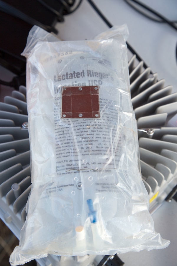 An IV-solution bag equipped with a metal plate is being prepped to be loaded on a Joint Tactical Aerial Resupply Vehicle (JTARV) for transport from a simulated forward operating base to a Marine special operations company in the field aboard Marine Corps Base Camp Pendleton, Calif., July 7, 2017. The JTARV, which is in the developmental phase, is a lightweight autonomous vehicle that provides an aerial resupply capability for immediate support to operational units. It was being tested as a resupply platform for machine-gun sustainment training with a cargo unmanned logistics system (C-ULS) during a tactical readiness exercise (TRX).