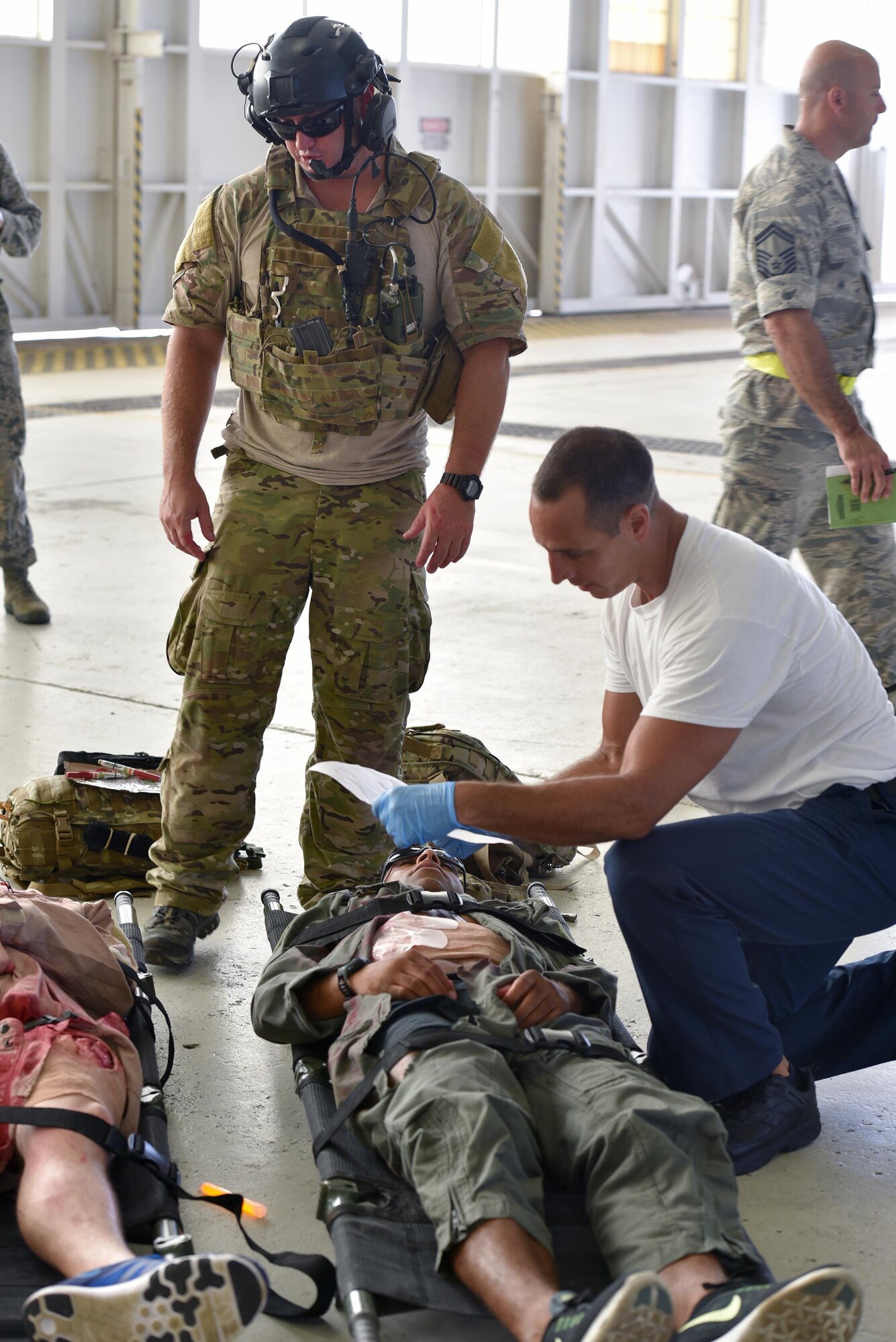 Matthew Martines, right, 45th Civil Engineer Squadron firefighter, receives a status update on a victim of an active shooter exercise, upon arriving on scene from Master Sgt. Louis Hause, 308th Rescue Squadron pararescueman, July 25, 2017 in Hangar 750. Pararescuemen worked closely with installation firefighters to tend to victims on scene and load them into ambulances for transport to the hospital. The joint exercise between the 920th Rescue Wing and 45th Space Wing tested the units’ ability to work together in an emergency situation. (U.S. Air Force photo/Tech. Sgt. Lindsey Maurice)