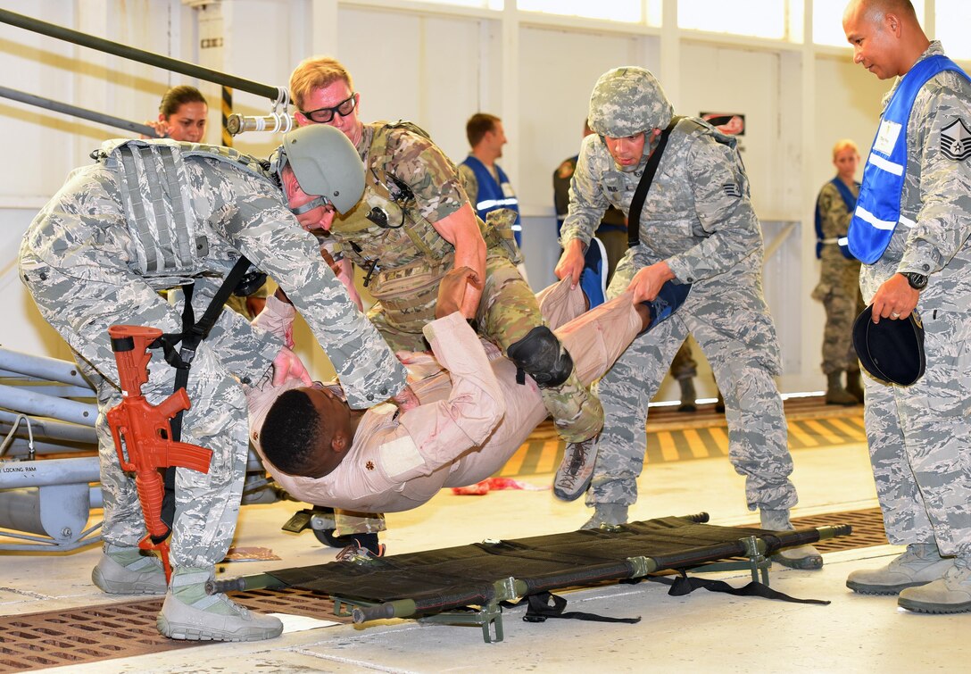 Staff Sgt. Stefan Laufenberg, left, and Staff Sgt. Jesse Ouverson, second from right, 45th Security Forces Squadron defenders, work with Staff Sgt. Lucus Vannorsdall, middle, 308th Rescue Squadron pararescueman, to lift an active shooter exercise victim onto a stretcher July 25, 2017 in Hangar 750. First responders from the host 45th Space Wing and tenant 920th Rescue Wing worked side-by-side to assist victims and ensure smooth transport to the hospital. The scenario included four injured Airmen and three deceased Airmen, including the active shooter. (U.S. Air Force photo/Tech. Sgt. Lindsey Maurice)