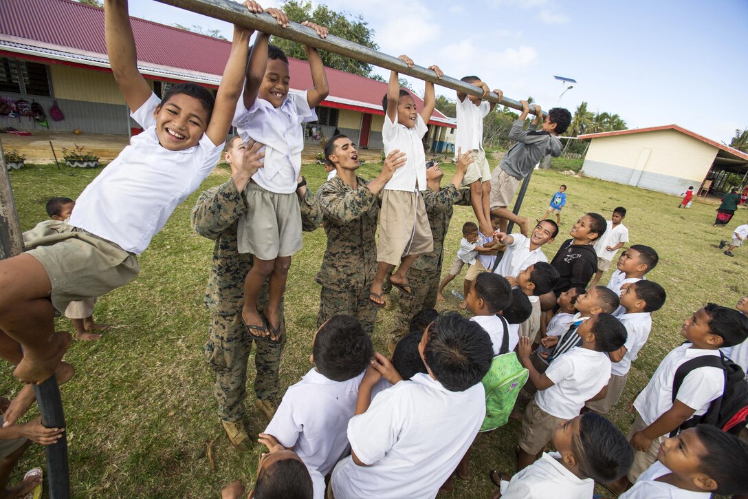 Marines help children do pullups while volunteering at an elementary school on the island of Tongatapu, Tonga, July 20, 2017. The Marines are assigned to Task Force Koa Moana 17. Marine Corps photo by Sgt. Douglas D. Simons