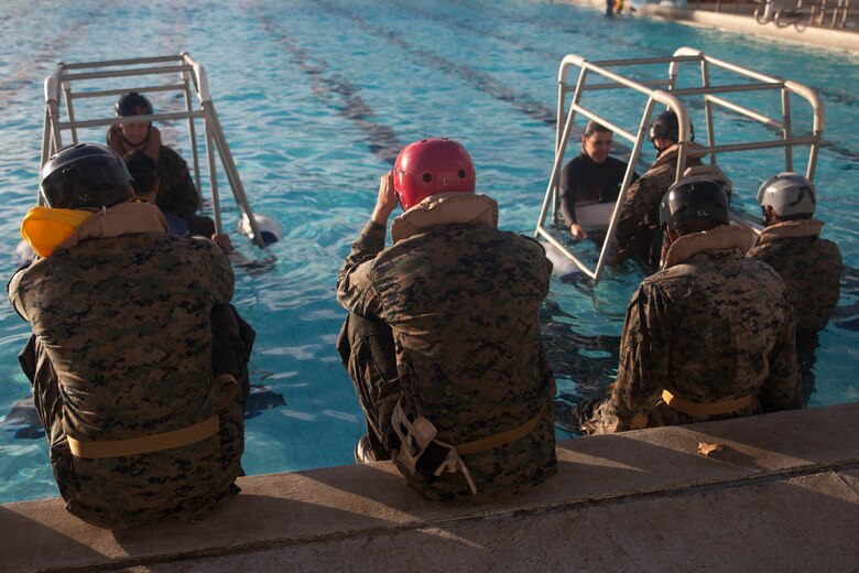U.S. Marines assigned to 3rd Marine Regiment, 3rd Marine Division, prepare to complete the Shallow Water Egress Training at the base pool aboard Marine Corps Base Hawaii, July 21, 2017. In the event of an Amphibious Assault Vehicle sinking, Submerged Vehicle Egress Training and Underwater Egress Training are vital training programs that prepares Marines and Sailors on safely escaping the vehicle. (U.S. Marine Corps photo by Lance Cpl. Matthew Kirk)