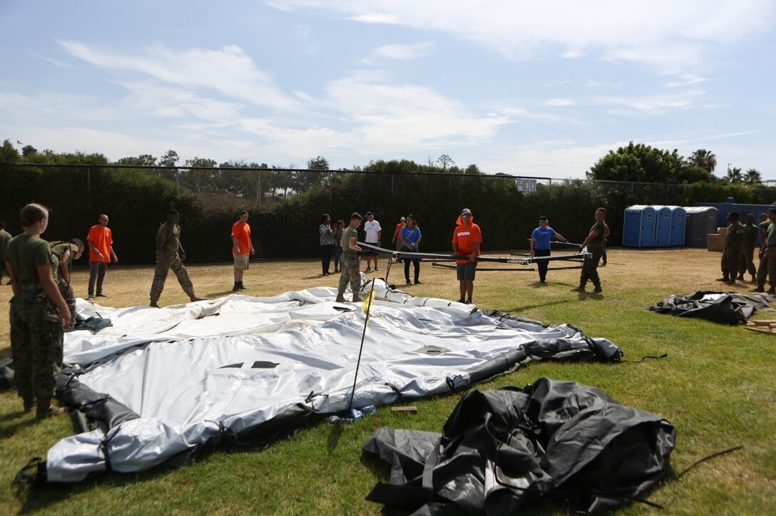 Marines with Marine Wing Support Squadron (MWSS) 373 and other volunteers set up tents for the Veterans Village of San Diego’s Homeless Veteran Stand Down at San Diego High School in San Diego, July 19. The Veterans Village of San Diego hosted the Homeless Veteran Stand Down to support homeless veterans by giving them a place to stay and providing services such as medical care, dental care, legal assistance, haircuts and food for three days. (U.S. Marine Corps photo by Cpl. Daniel Auvert/ Released)