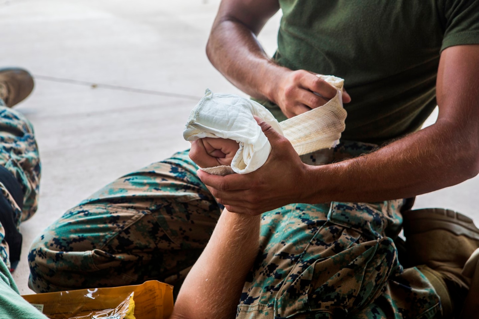 CAMP PENDLETON, Calif. – U.S. Marine Lance Cpl. Laine Fife, a marksmanship coach with the Marksmanship Training Unit, Headquarters Company, Headquarters Regiment, 1st Marine Logistics Group, uses gauze to wrap up a wounded hand during the practical application portion of a combat lifesaver course July 22, 2017. Through the CLS course, Marines add combat casualty care to their arsenal of individual capabilities. (U.S. Marine Corps Photo by Lance Cpl. Joseph Sorci)