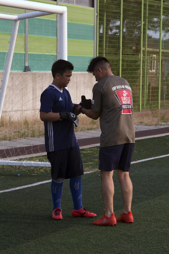 Lance Cpl. Jose Casias helps a goalie put on his gloves July 20 in Pohang, Republic of Korea. Casias volunteers his weeknights to coach a local youth soccer team. He also teaches English classes at different grade schools and kindergartens, as well as participating in clean ups throughout the community near Camp Mujuk. Casias, an Atlanta, Georgia, native is a bulk fuel specialist with Camp Mujuk Headquarters Logistics, Marine Corps Installations Pacific. (U.S. Marine Corps photo by Sgt. Jessica Collins)