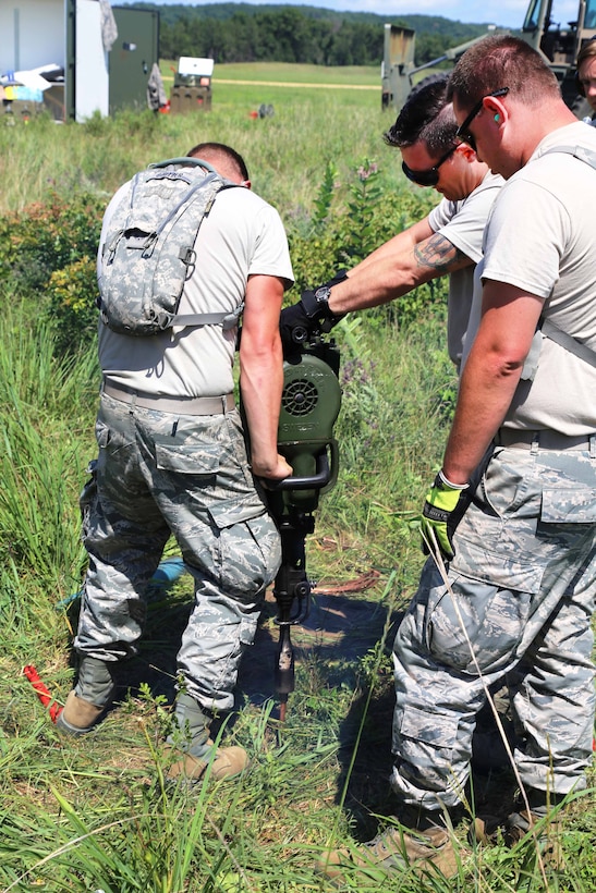 Oregon Air National Guardsmen drill a hole before setting up equipment for a mobile tower and a tactical air navigation system to allow for air traffic control operations during the Patriot North 2017 exercise at the Young Air Assault landing strip at Fort McCoy, Wis., July 17, 2017. Army photo by Scott T. Sturkol