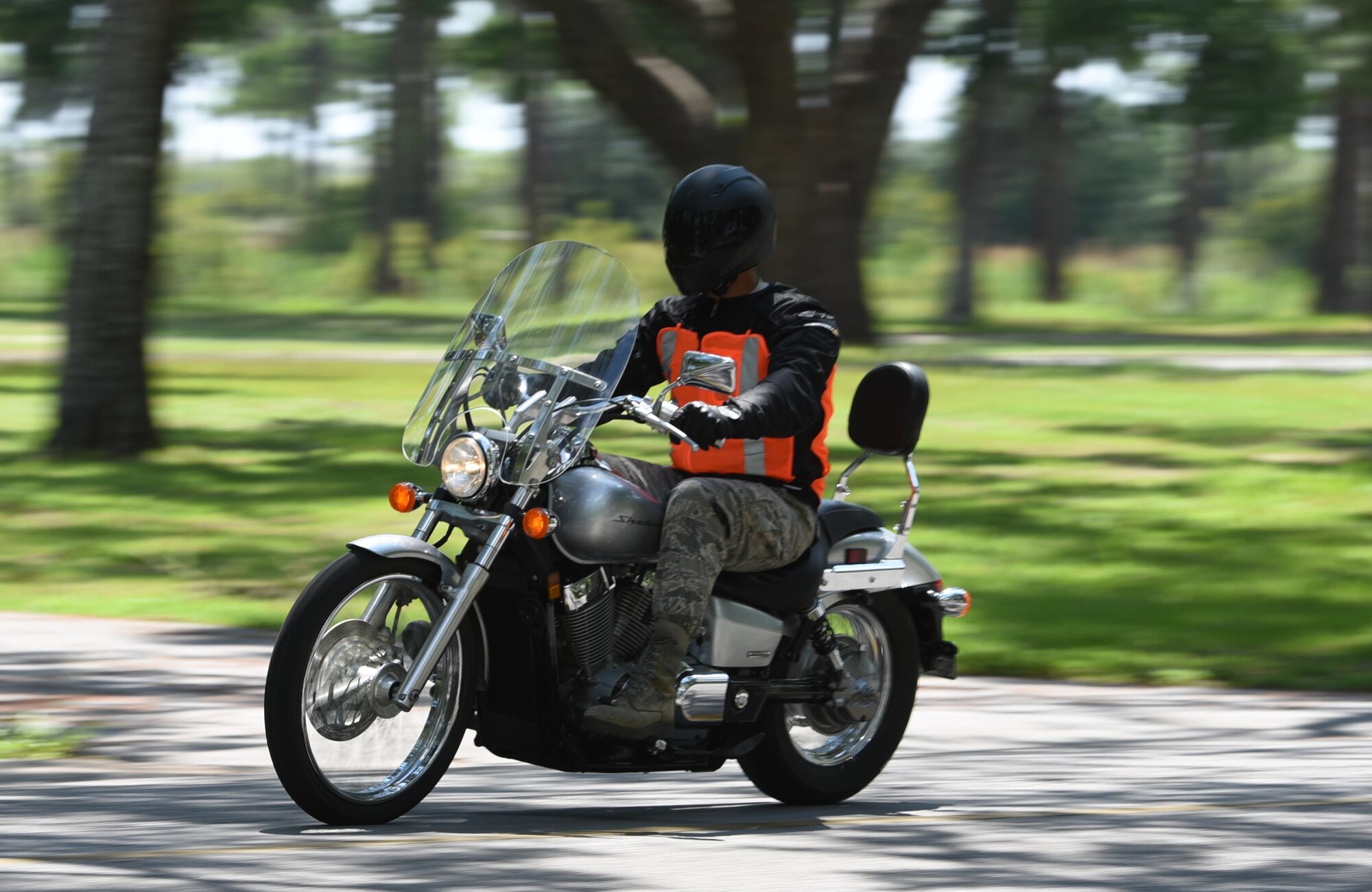 A Tyndall Airman rides a motorcycle down a street near the Heritage Club on Tyndall Air Force Base, Fla., while wearing the necessary personal protective equipment. July 27, 2017. To adhere to Air Force Instruction 91-207 The U.S. Air Force Traffic Safety Program, Airmen must wear at a minimum: head protection, eye protection, study over-the-ankle footwear, long-sleeved shirt or jacket, long trousers and full fingered gloves or mittens made of leather or abrasion-resistant material. Riders are encouraged to select PPE that incorporates fluorescent colors and retro-reflective material. (U.S. Air Force photo by Airman 1st Class Isaiah Soliz/Released)