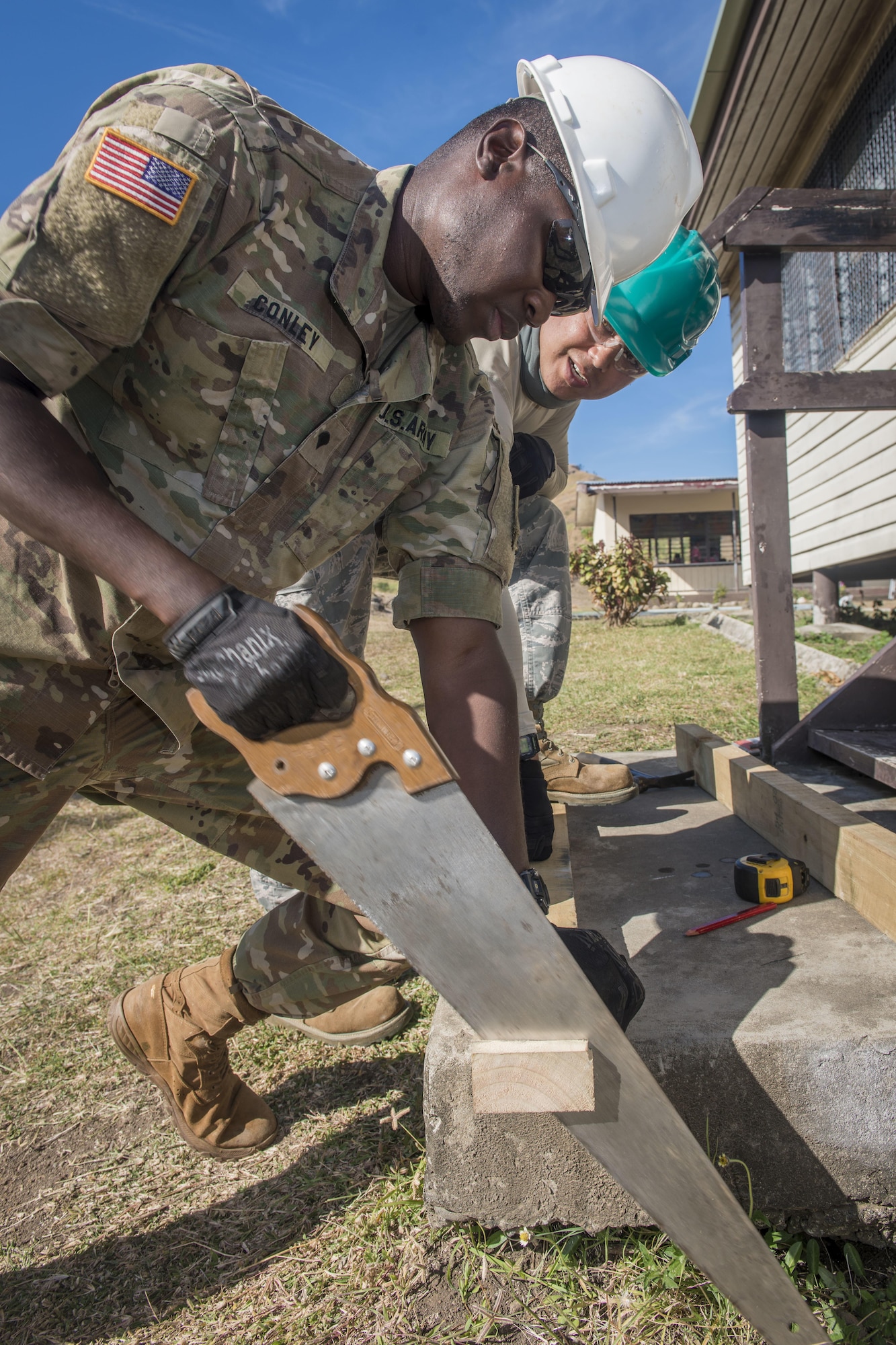 U.S. Army Spc. Solomon Conley, a carpentry and masonry specialist with the 523rd Engineer Company at Schofield Barracks, Hawaii, cuts a board to length as U.S. Air Force Staff Sgt. Kyle Quinata, a structural engineer with the 254th Red Horse Squadron at Andersen Air Force Base, Guam, observes during Pacific Angel (PACANGEL) 17-3 at Karave Primary School in Ba, Fiji, July 18, 2017. Conley and Quinata worked together to rebuild steps to a schoolhouse while others on their engineering team reconstructed roofing supports and new plumbing installed. Service members from more than five nations joined the U.S. to work together to rebuild certain areas of Fiji during PACANGEL 17-3. (U.S. Air Force photo/Tech. Sgt. Benjamin W. Stratton)