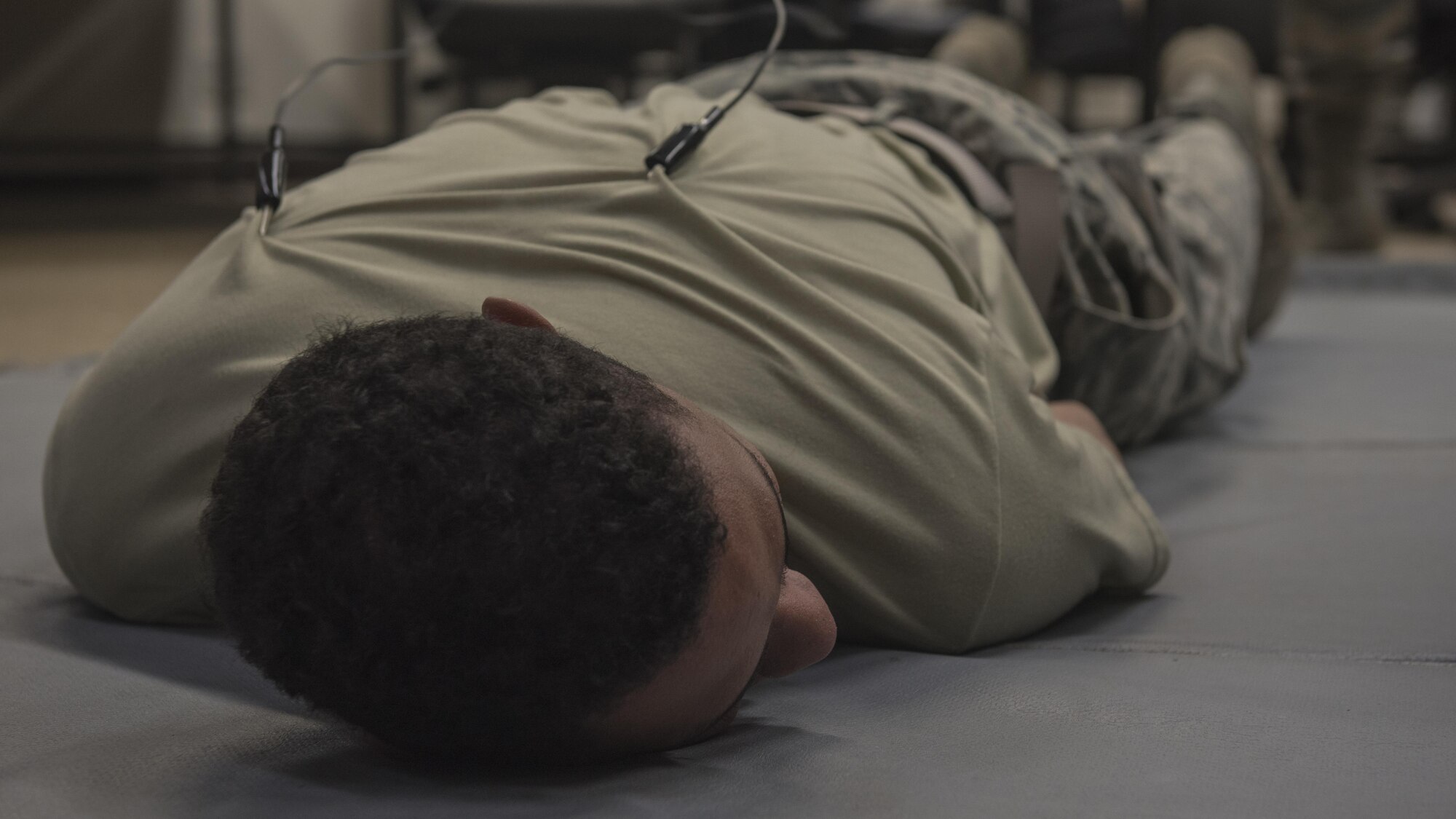U.S. Air Force Airman 1st Class Jamsen Hayden, 18th Security Forces Squadron defender, lays down for a demonstration of the ‘ride the lightning’ during Taser and oleoresin capsicum (OC)  spray training July 20, 2017, at Kadena Air Base, Japan. Defenders were able to choose what position they preferred to be in for this portion, including laying down, or having the clips attached to their abdomen, calves, or standing up. (U.S. Air Force photo/ Airman 1st Class Greg Erwin)