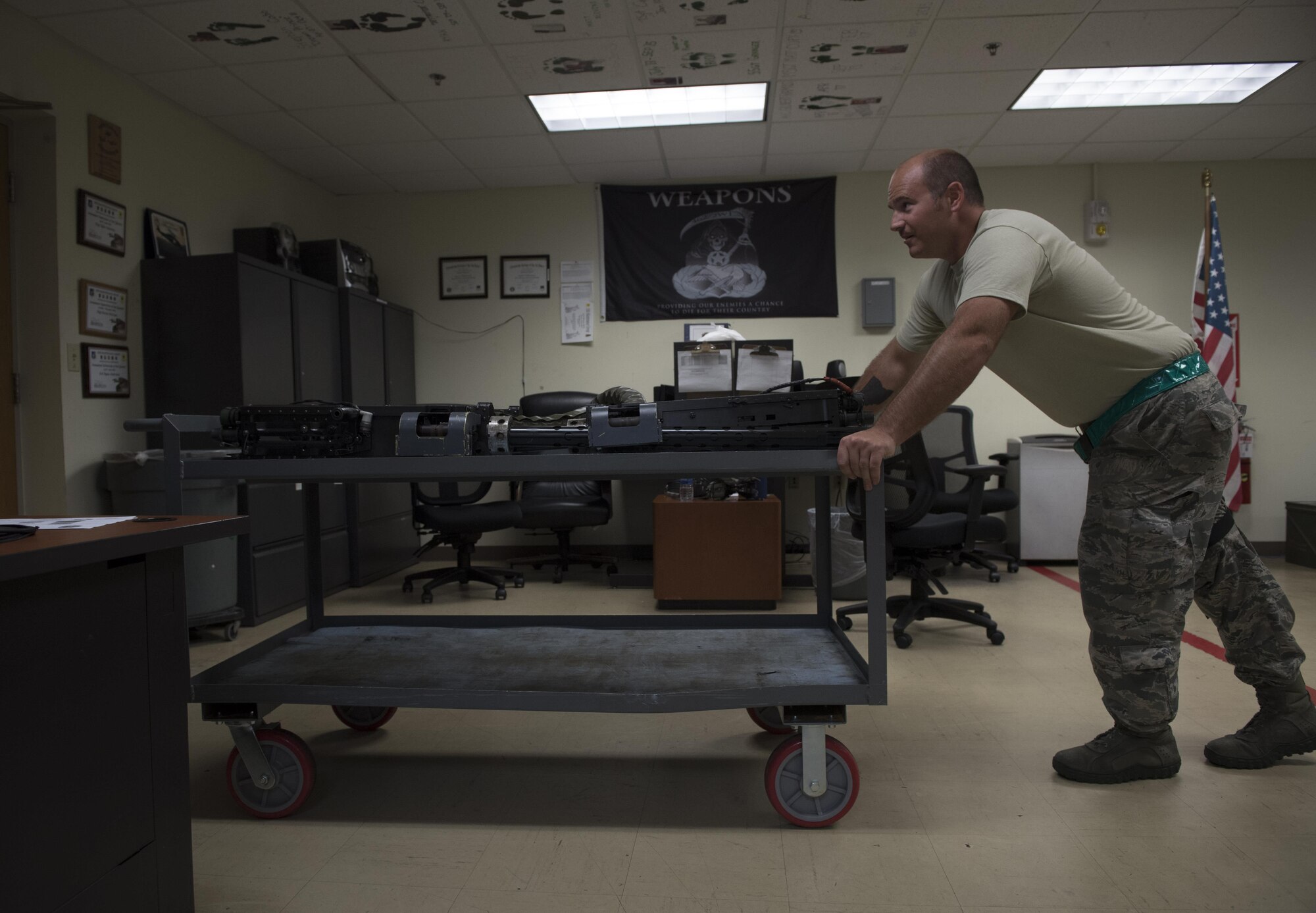 U.S. Air Force Senior Airman Zachary Hough, 33rd Helicopter Maintenance Unit weapons section weapons load crewmember, moves a cart of Gau-18 50-caliber machine guns July 26, 2017 at Kadena Air Base, Japan. Airmen in the weapons section maintain, install, remove and safeguard all armaments and items associated with the HH-60 gun mounting and ammunition handling systems for the 33rd Rescue Squadron. (U.S. Air Force photo by Senior Airman John Linzmeier)