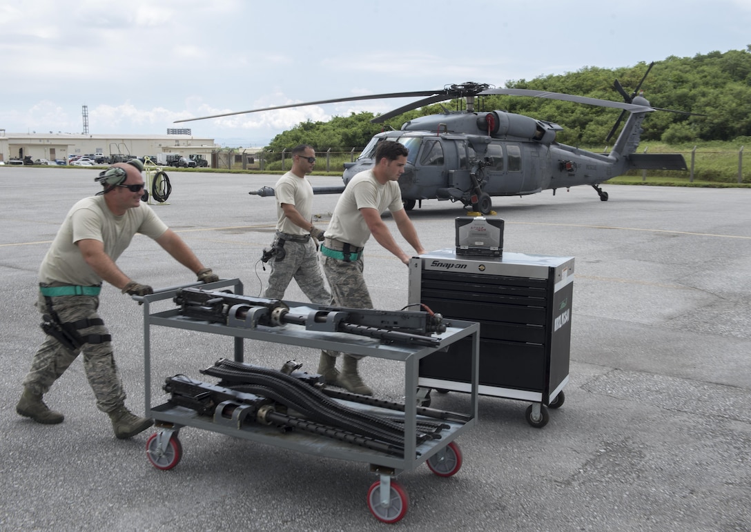 U.S. Air Force Senior Airman Zachary Hough, Tech. Sgt. Josean Arce and Staff Sgt. Ryan Anderson, 33rd Helicopter Maintenance Unit weapons section weapons load technicians, transport GAU-18 50-caliber machine gun toward an HH-60 Pave Hawk from the 33rd Rescue Squadron July 26, 2017, at Kadena Air Base, Japan. The weapons section provides defensive-counter-air lethality to nine HH-60 Pave Hawks from the 33rd Rescue Squadron. (U.S. Air Force photo by Senior Airman John Linzmeier)