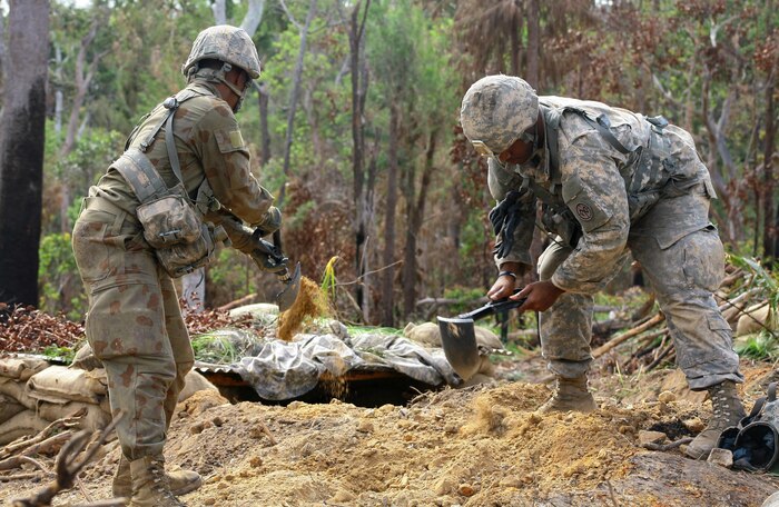 Spc. Shawn Tillery and Pfc. Vaquine Stewart, both infantrymen assigned to Alpha Company, 1st Battalion, 69th Infantry Regiment of the New York Army National Guard, use their entrenching tools to expand their fighting position in anticipation of an assault  at Shoalwater Bay, Queensland, Australia during exercise Talisman Saber, July 14, 2017. They are wearing a mix of Australian and American uniform items because of their role as opposing force. During the exercise New York Army National Guard Soldiers fought against an Australian Defense Force Brigade during a week-long series of war games. (U.S. Army National Guard photo by Sgt. Alexander Rector)
