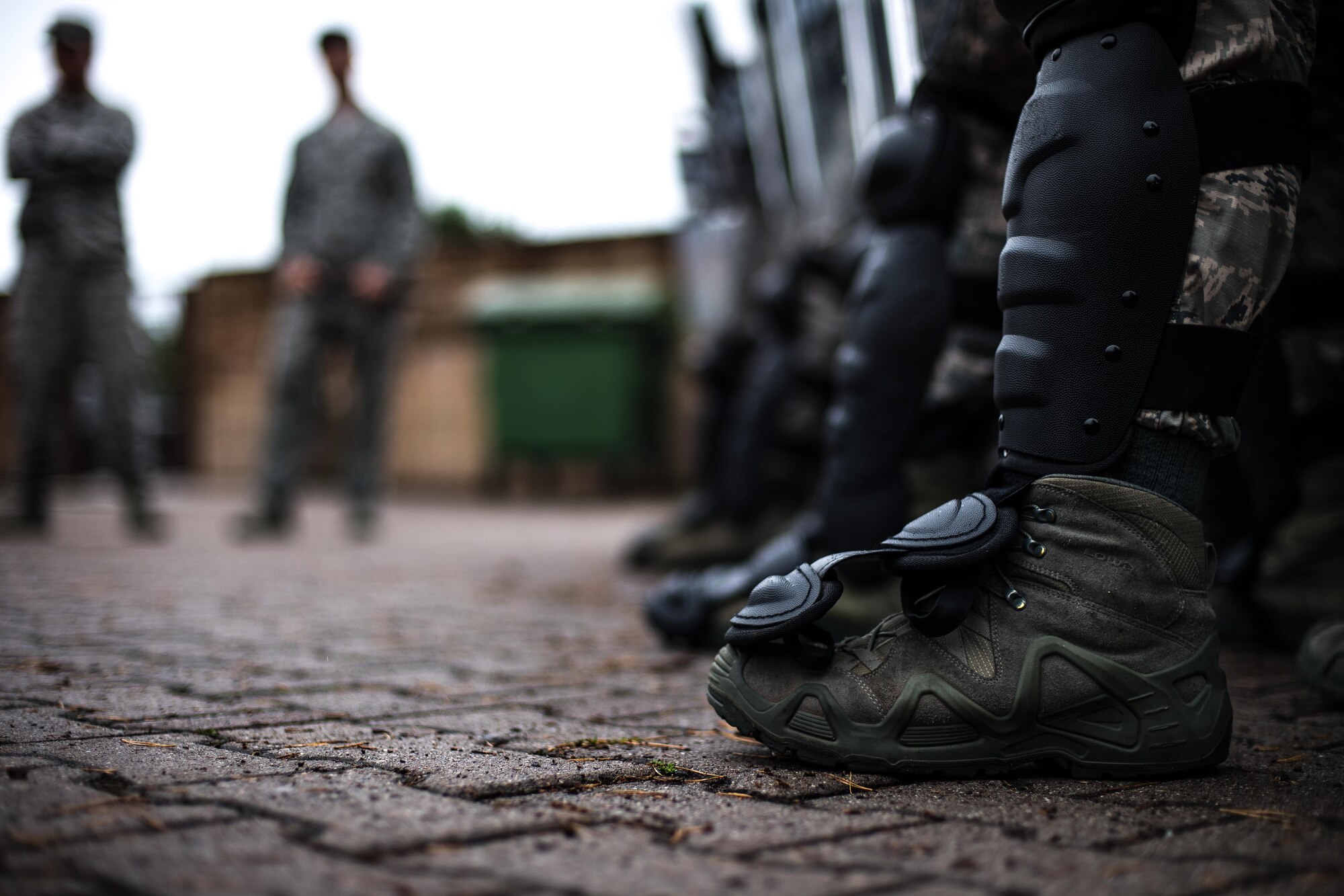 U.S. Airmen assigned to the 86th Security Forces Squadron hold their position during confrontational management training at the 86th SFS training section on Ramstein Air Base, Germany, July 25, 2017. Security forces use shin guards to protect themselves from thrown projectiles as well as crowds attempting to push through the line. (U.S. Air Force photo by Senior Airman Devin Boyer)