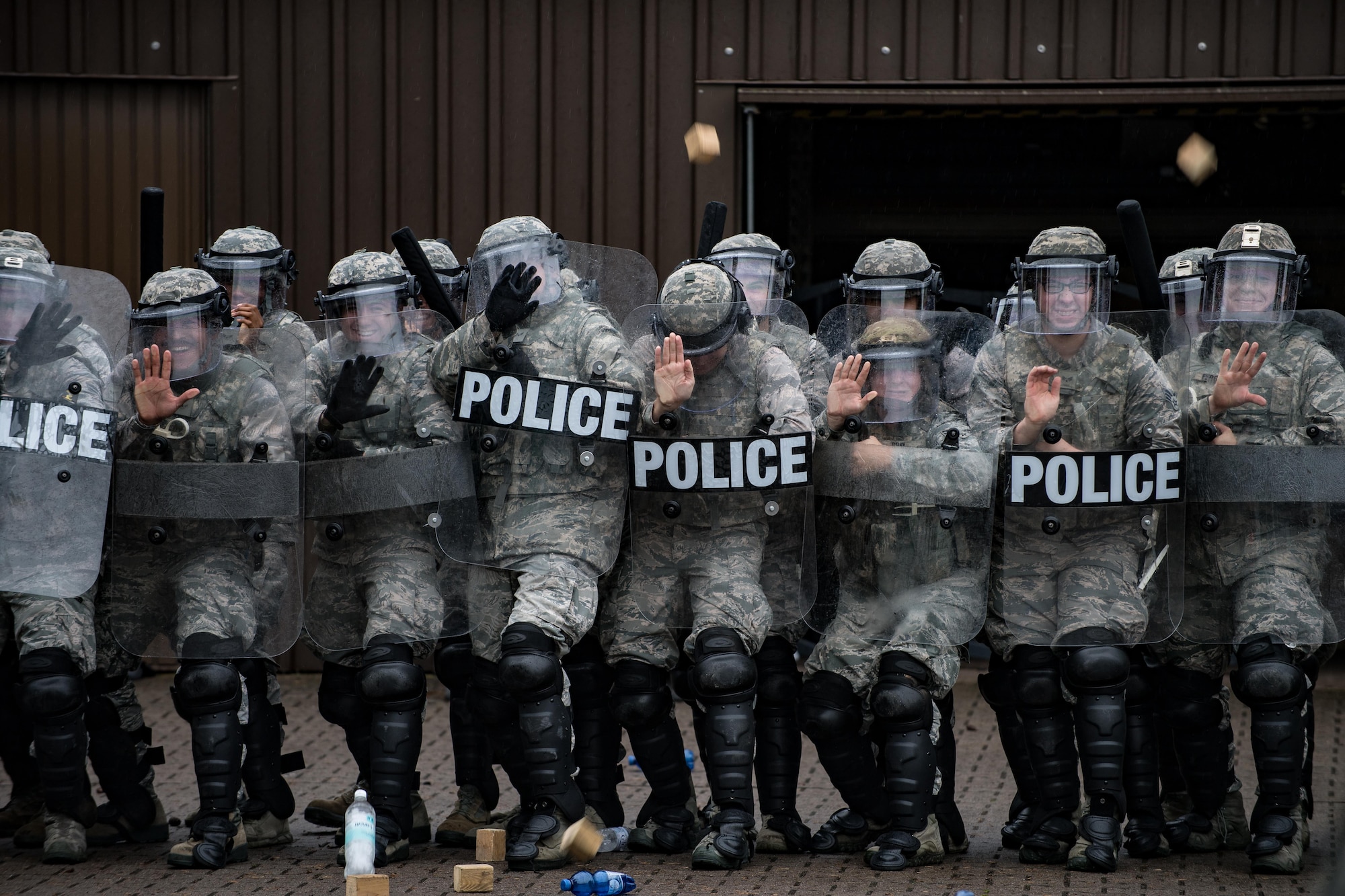 U.S. Airmen assigned to the 86th Security Forces Squadron hold their position during confrontational management training at the 86th SFS training section on Ramstein Air Base, Germany, July 25, 2017. To make the training realistic, Airmen threw blocks and water bottles at the security forces members’ shields while they held their position. (U.S. Air Force photo by Senior Airman Devin Boyer)