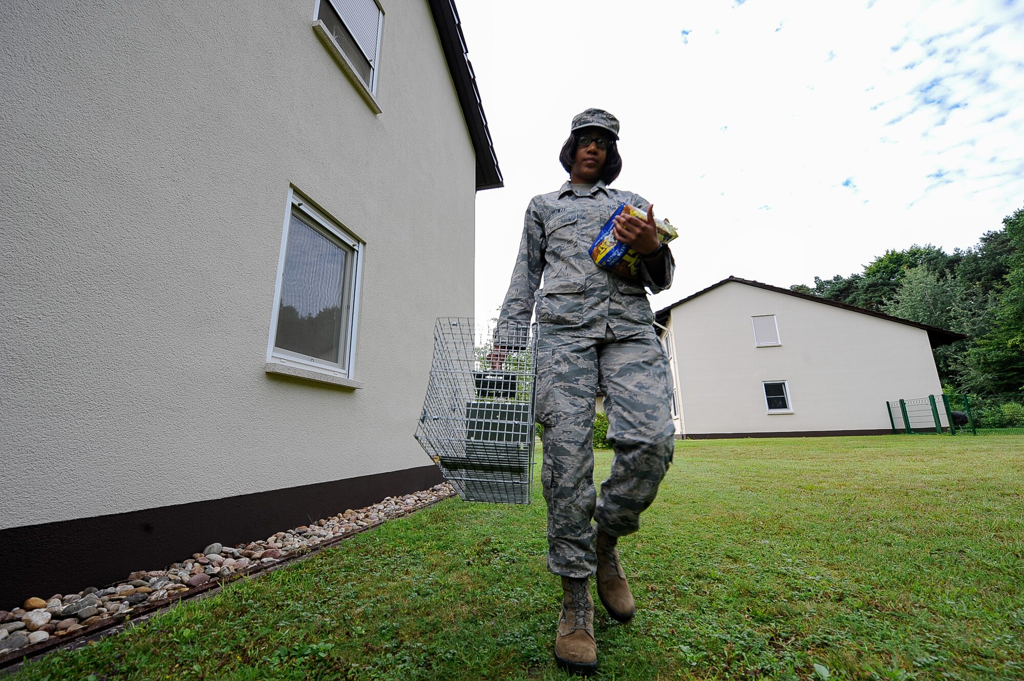 Airman 1st Class Arielle Howze, 786th Civil Engineer Squadron pest management journeyman, brings an animal trap to Vogelweh Housing on Vogelweh Military Complex, Germany, July 28, 2017.  Stray cats are common in housing and dorms areas, and pest management technicians use baited traps to capture them. (U.S. Air Force Airman 1st Class Savannah L. Waters)