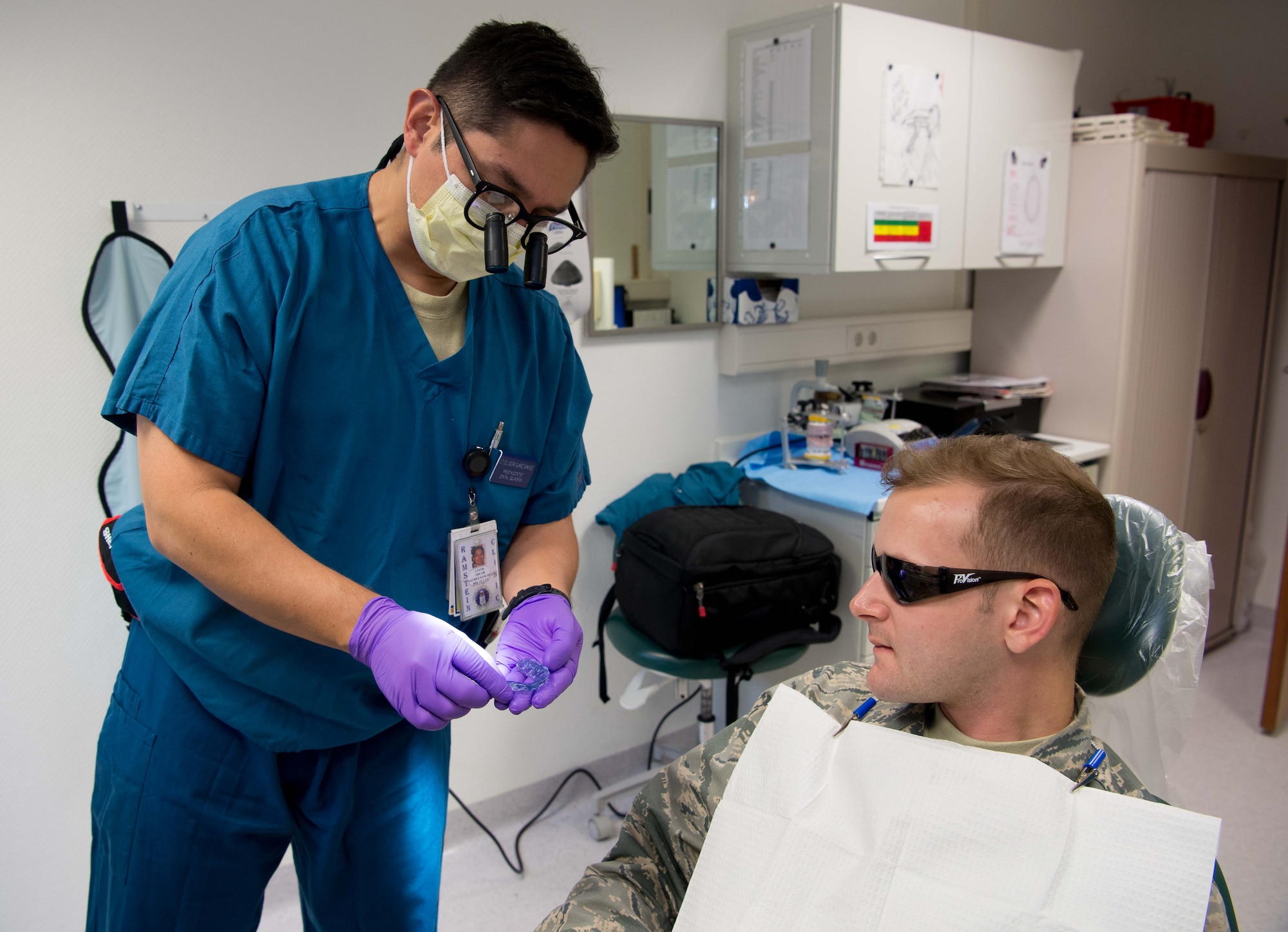 U.S. Air Force Lt. Col. Oscar Suarez-Sanchez, 86th Dental Squadron base dental laboratory flight commander, shows Senior Airman William Pratt, 1st Air Communications Operations Squadron cyber systems operator, a tool used to correct Pratt’s bite on Ramstein Air Base, Germany, July 25, 2016. Suarez-Sanchez, who has a passion for taking better care of patients, is implementing rapid response teams to cut recovery time for dental trauma patients. (U.S. Air Force photo by Senior Airman Elizabeth Baker)