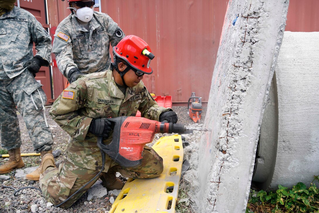 A Hawaii Army National Guardsman drills holes in debris to allow team members to locate possible mock casualties during a combined training exercise in Kalaeloa, Hawaii, July 18, 2017. Air National Guard photo by Tech. Sgt. Andrew Jackson