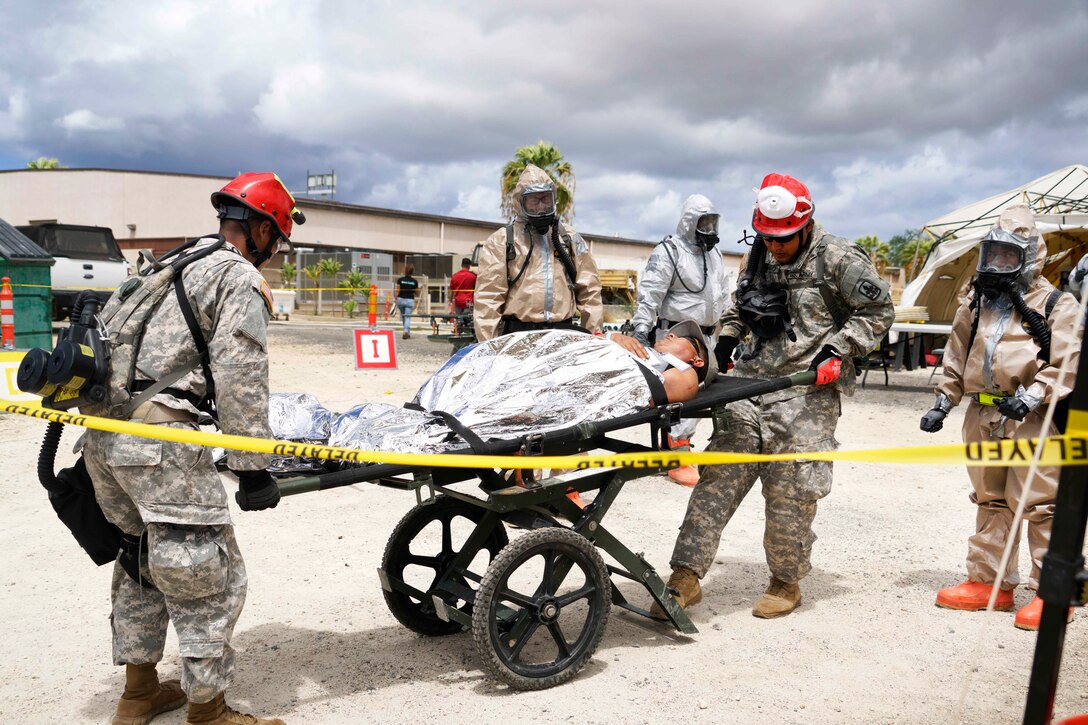Hawaii Army National Guardsmen transport a mock casualty on a gurney to an area for decontamination and medical treatment during a combined training exercise in Kalaeloa, Hawaii, July 19, 2017. Air National Guard photo by Tech. Sgt. Andrew Jackson