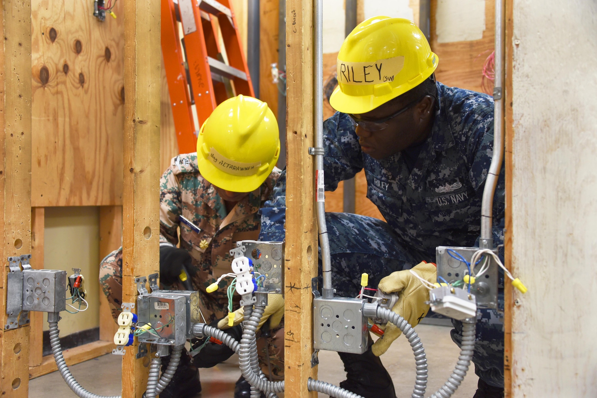 Major Ashrar Altarawneh and Seaman Devon Riley, 366th Training Squadron electrical systems apprentice course students install the duplex receptacle 120 volts switch at Sheppard Air Force Base, Texas. This course provides initial training for students to perform installation and maintenance duties of interior electrical systems. (U.S. Air Force photo/Liz H. Colunga)