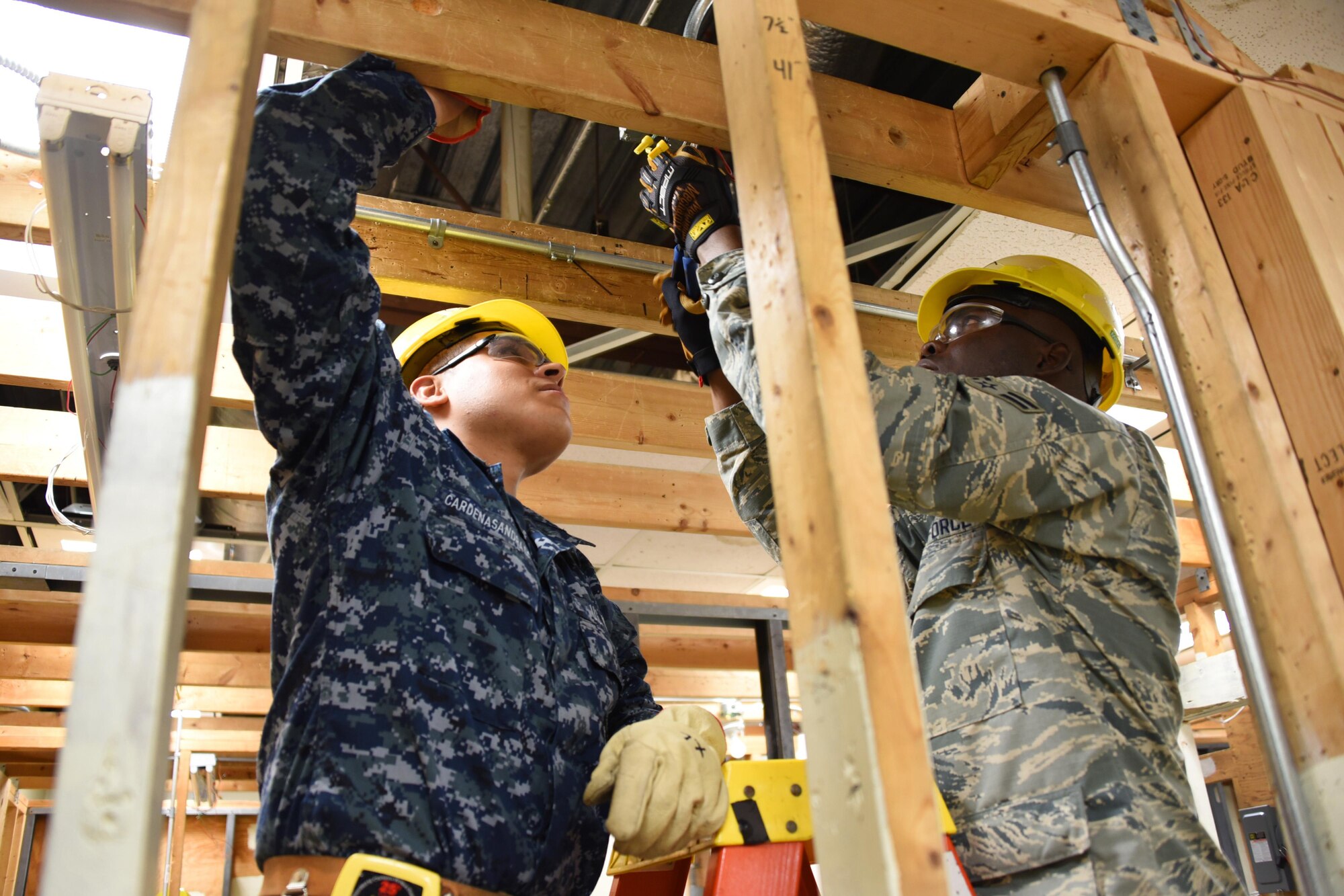 Seaman Salvador Cardenas-Andrade and Airman Henneh Kota, 366th Training Squadron electrical systems apprentice course students perform the wiring of a junction box at Sheppard Air Force Base, Texas. This course provides initial training for students to perform duties in installation and maintenance of interior electrical systems. (U.S. Air Force photo/Liz H. Colunga)