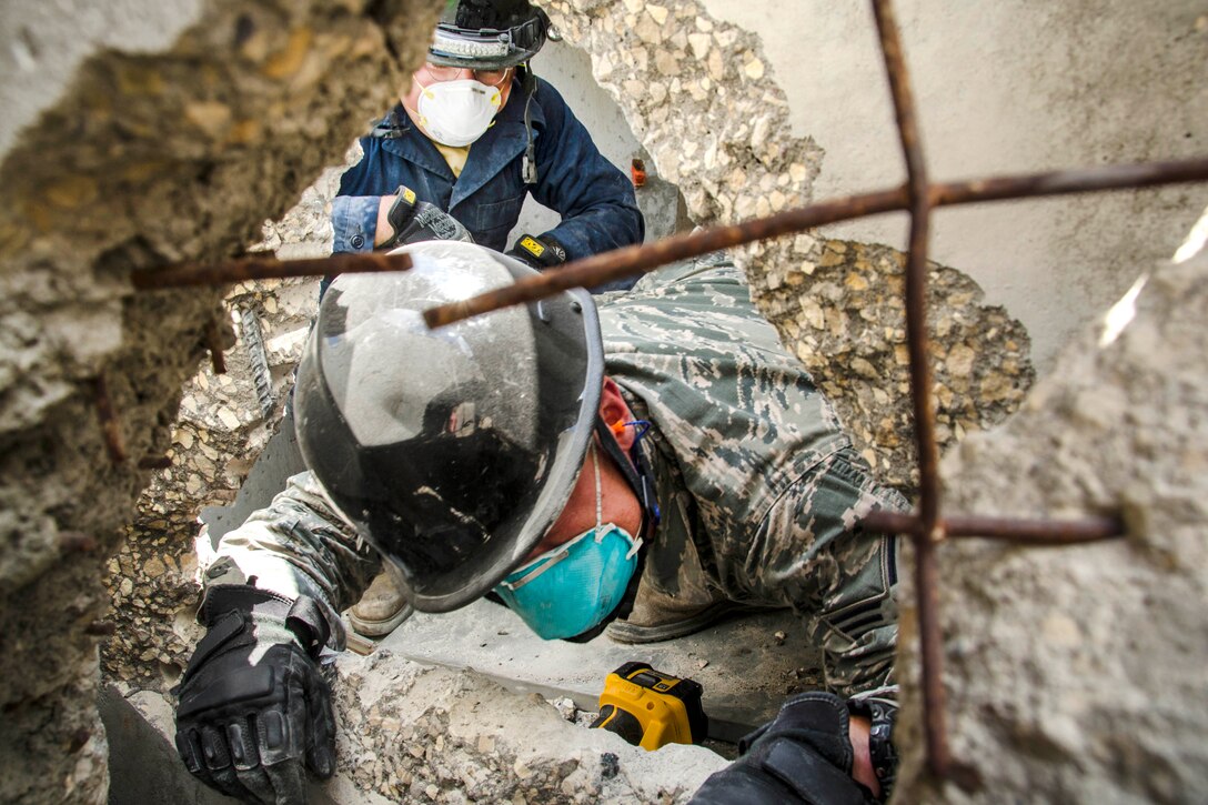Air National Guardsmen search through rubble and debris after cutting a hole in a concrete wall during a simulated search and rescue as part of the Patriot North exercise at Volk Field, Wis., July 18, 2017. Air National Guard photo by Master Sgt. Kellen Kroening