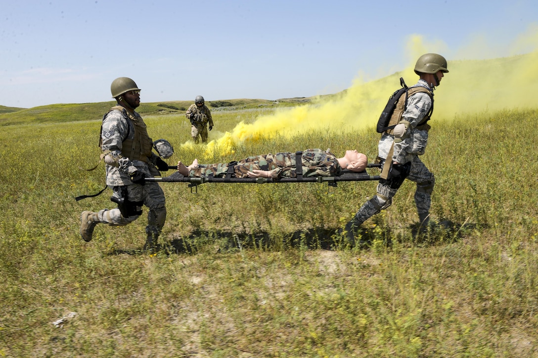 Two airmen run with a simulated battle casualty on a litter during training.