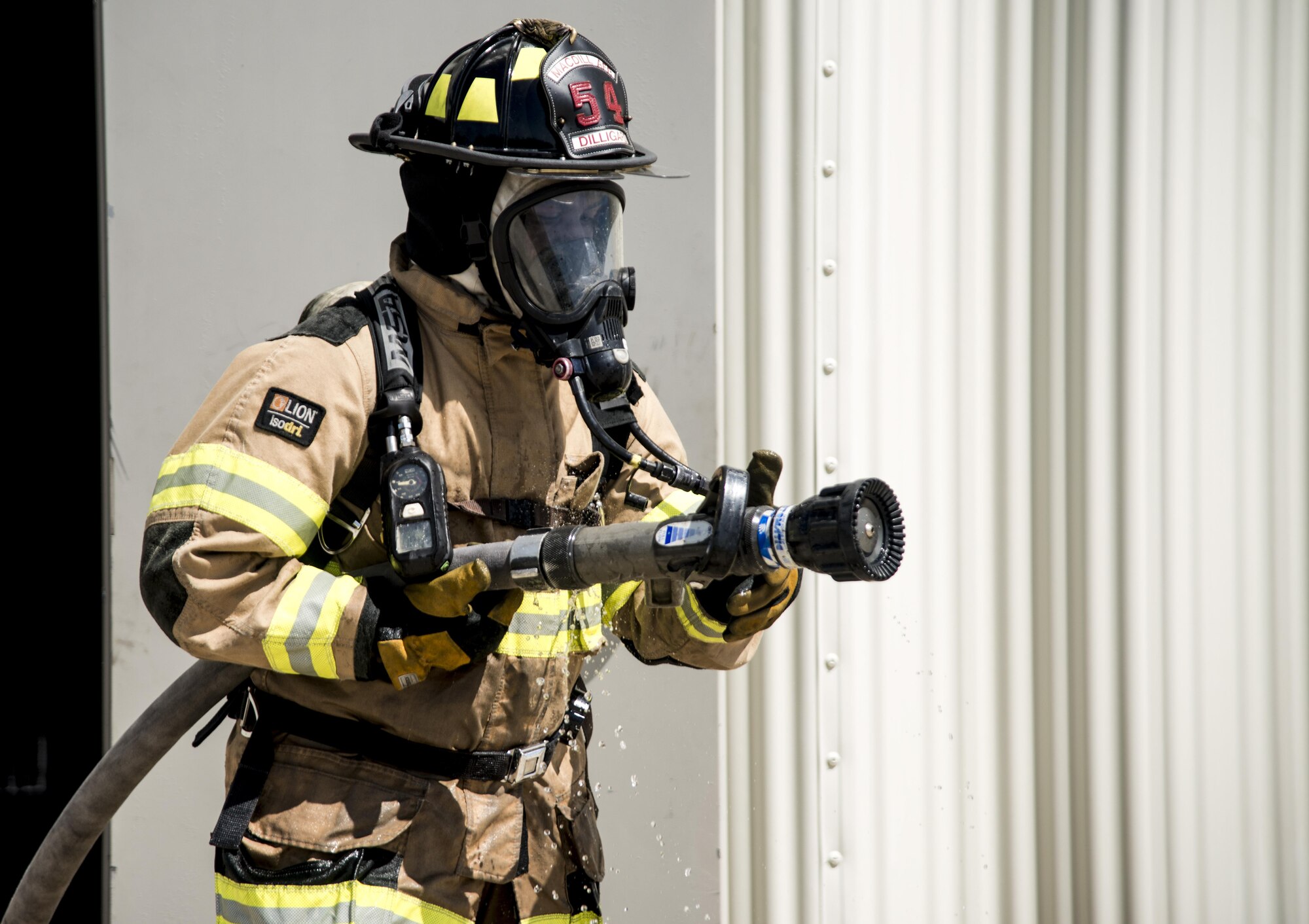 U.S. Air Force Senior Airman Montel Dilligard, a firefighter assigned to the 6th Civil Engineer Squadron, turns off a hose after the team successfully extinguished a training fire at MacDill Air Force Base, Fla., July 24, 2017. The firefighters conducted a structural, live-burn exercise to show Airmen the behavior of a fire inside a building. (U.S. Air Force photo by Airman 1st Class Adam R. Shanks)