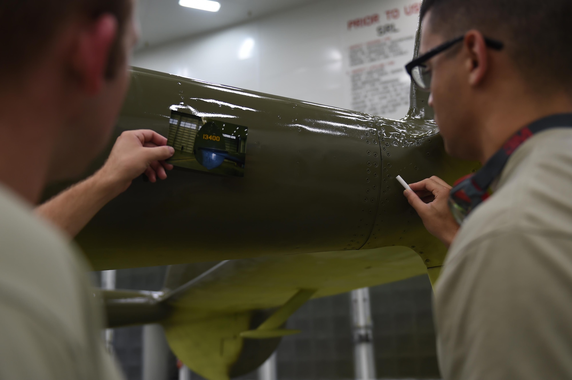 Air Force Senior Airman Kurtis Steinecke (left) and Airman 1st Class Jonathan Torres-Zaya put the final touches on the P-38G Lightning before it can be returned to the Heritage Park at Joint Base Elmendorf-Richardson, Alaska, July 20, 2017. 