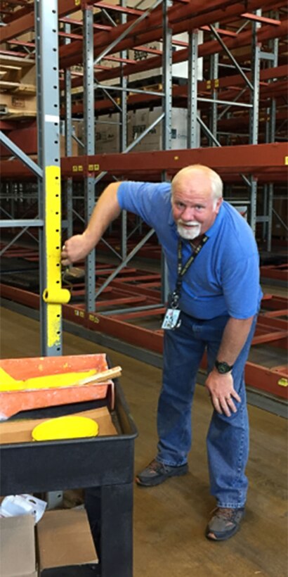 Lawrence "Mac" McNinch of DLA Disposition Services at Columbus applies yellow paint to a storage rack risers in an attempt to increase their visibility. 