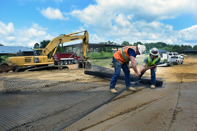 Two contractors cut a geogrid fabric which will help stabilize the Northport levee. Approximately 3,000 cubic yards of debris and soil has been removed and disposed of, while relocating and importing close to 10,000 cubic yards of compacted suitable soils.