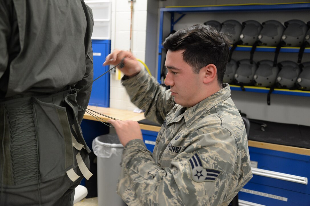 Senior Airman Carlos Garza, 80th Operations Support Squadron aircrew flight equipment technician, tightens the laces on the back of a pilots G-suit to fit there exact size. Garza hand fits each suit to the individual pilot to ensure proper fit and function. (U.S. Air Force photo by Senior Airman Robert L. McIlrath)